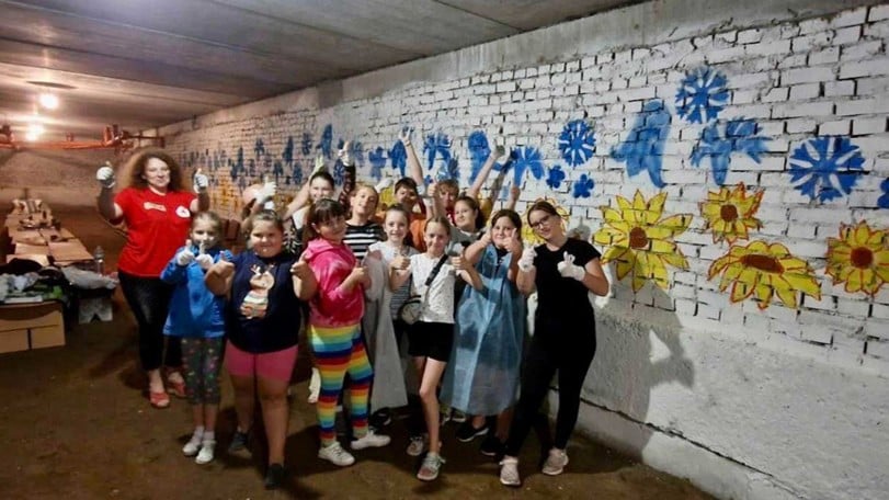 Ett gäng barn målar väggarna i en skolas skyddsrum i staden Lviv.