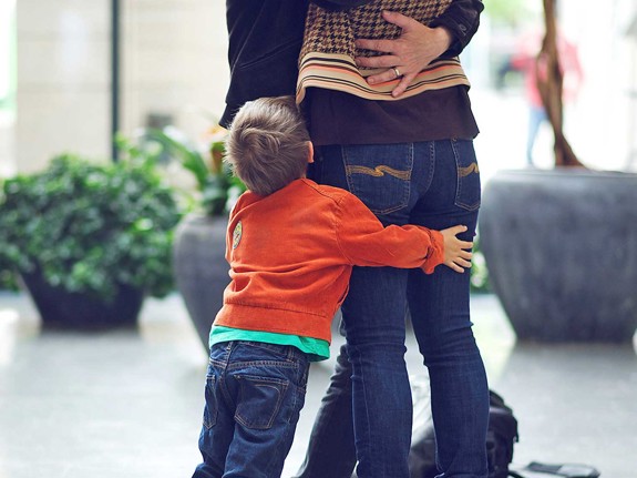 Barn kramar om benen på vuxen