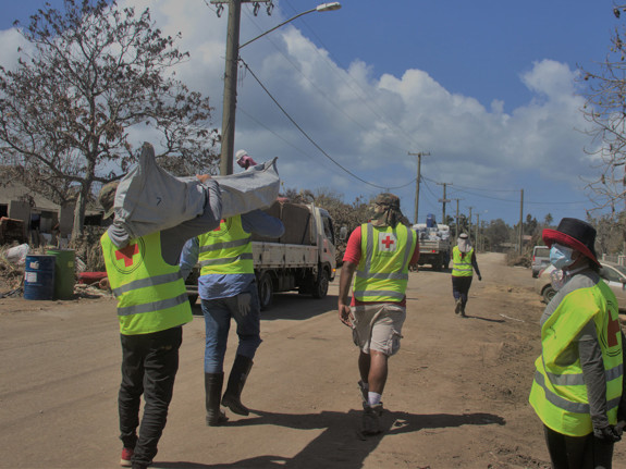 Röda Korset volontärer bär säckar med nödhjälp