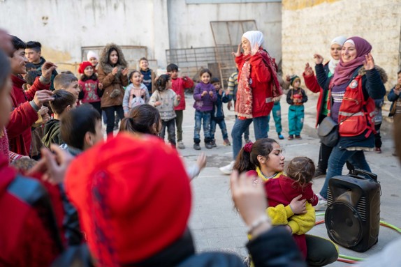 Barn leker tillsammans volontärer i Syrien.