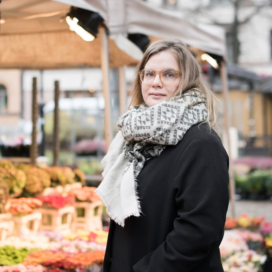 Johanna Lönn står på ett torg framför ett blomstånd.