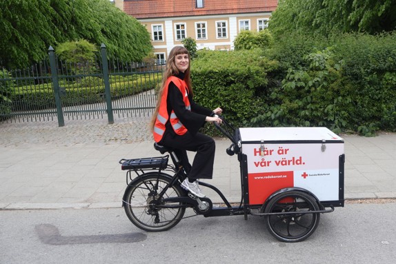 Bild på volontären Ida som förekommer i texten, hon sitter vid en lådcykel med Röda Korsets logga på.