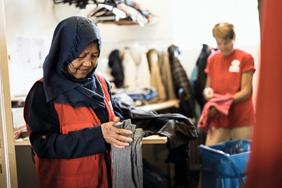 Två personer viker kläder i second hand-butiken.