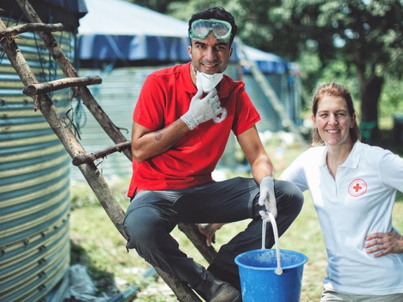 Farzad Farzaneh och Röda Korskollega framför vattenreningsverk i Uganda.