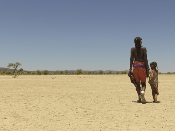 Kvinna och barn går genom Namibias öken.