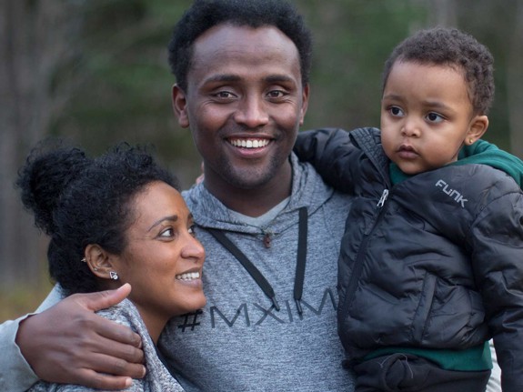 Leende man kramar kvinna och pojke