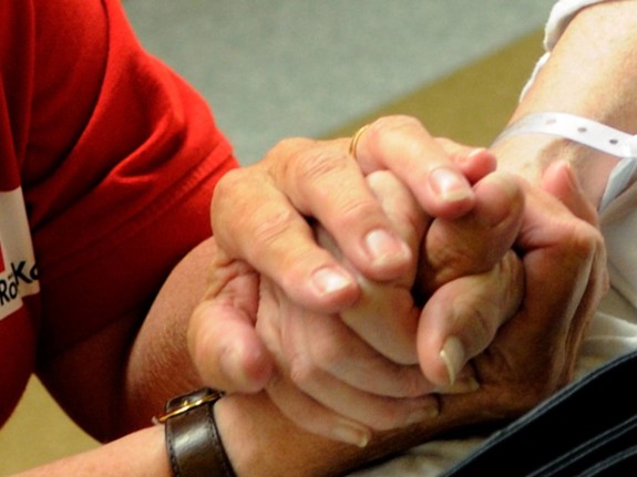 En volontärs hand håller i en patients hand