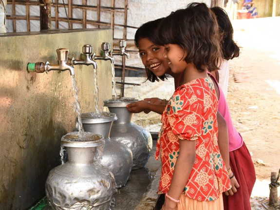 Flickor fyller stålflaskor med vatten