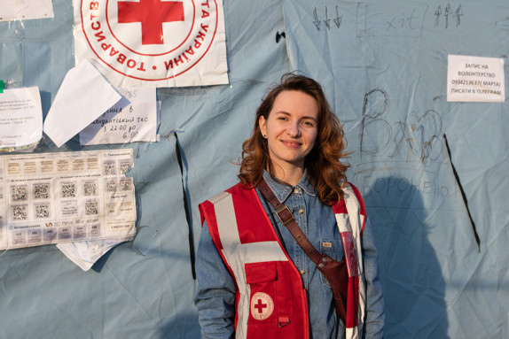 Julia, volontär i Ukrainska Röda Korset, står framför ett tält.