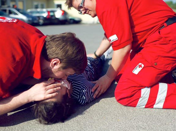 Första hjälpen-grupp har övning och hjälper en medvetslös person med hjärtlungräddning, HLR