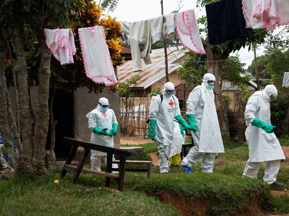 Människor i skyddsdräkt går igenom by