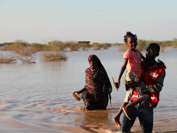 Röda kors-frivllig bär barn genom vatten.