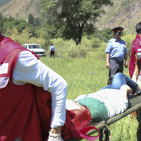 En man bärs på bår av Röda Korsets volontärer.