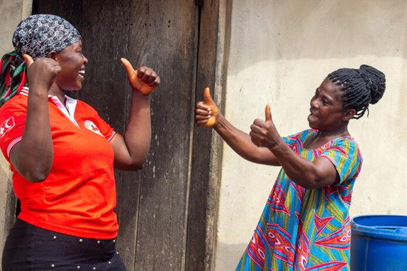 Joyce Oforiwah ger Röda Korsets volontär Regina Nyamevor tummen upp för hjälpen med rent dricksvatten.