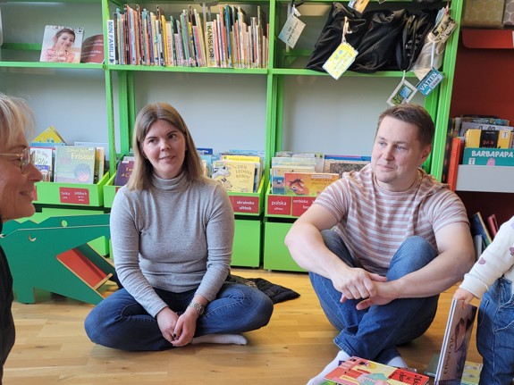 Föräldrarna Moa och Jens sitter på golvet och deras barn leker intill.