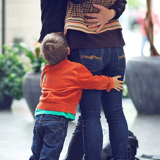 Liten pojke kramar om föräldrars ben