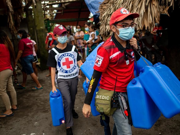 Röda Korset-volontärer bär blåa dunkar.