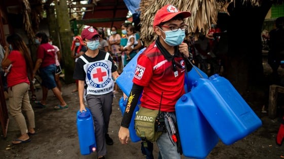 Röda Korset-volontärer med blåa dunkar.