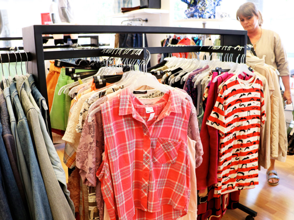 Syntolkning: En volontär hänger upp kläder i en second hand-butik.