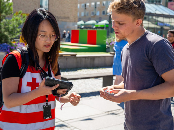 En värvare i Röda Korset-kläder visar innehåll på sin tablet för en potentiell givare.