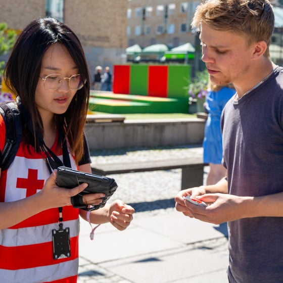 En värvare i Röda Korset-kläder visar innehåll på sin tablet för en potentiell givare.
