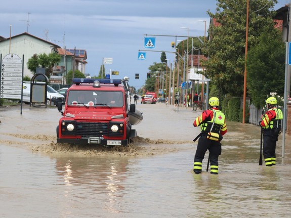 Män och bil på översvämmad gata i Italien