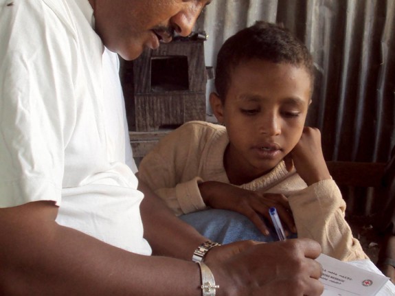 Ett barn får hjälp att skriva ett Rödakorsmeddelande.