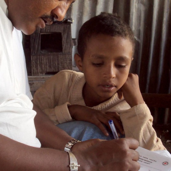 Ett barn får hjälp att skriva ett Rödakorsmeddelande.