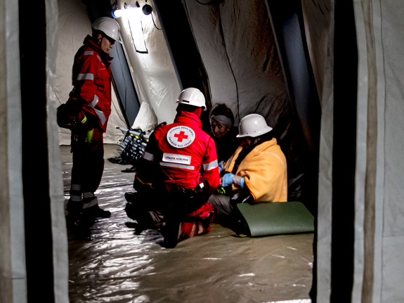 Två volontärer från Röda Korset hjälper två personer i ett tält under en krisövning.