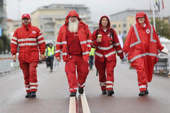 Fyra person vandrar på en väg, de har kläder på sig som visar att de kommer från Röda Korset.