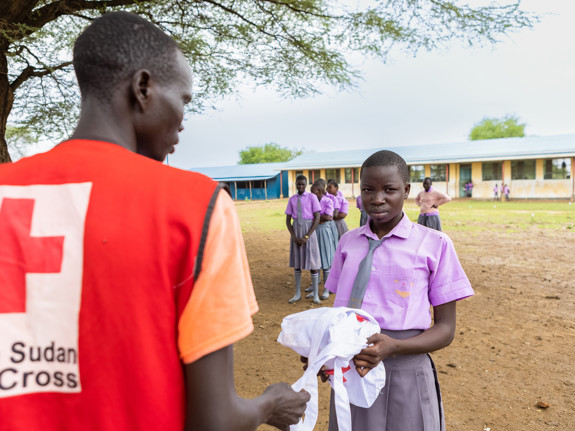 Röda Korset volontär delar ut mensskydd i skola