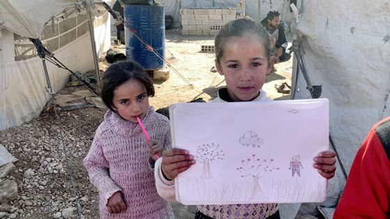Barn visar upp teckning i lägret