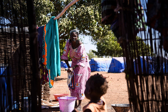 Kvinna i flyktingläger handtvättar kläder i hink
