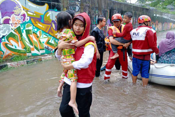 Far bär på son på översvämmad gata i Indonesien