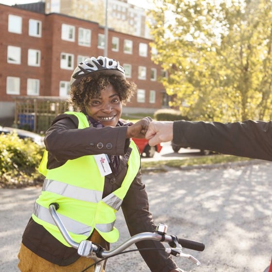 Rödakorsare hälsar på ungdom i cykelhjälm