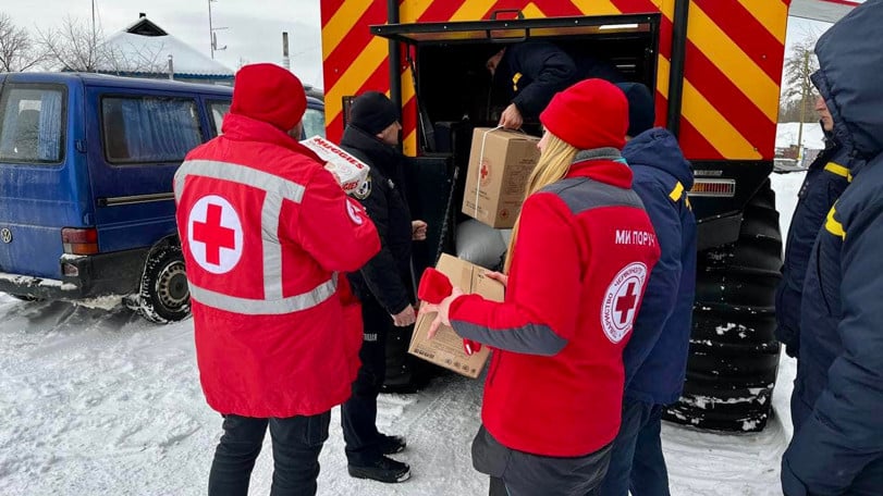 Två Röda Korset-volontärer lastar av nödhjälp från en lastbil.