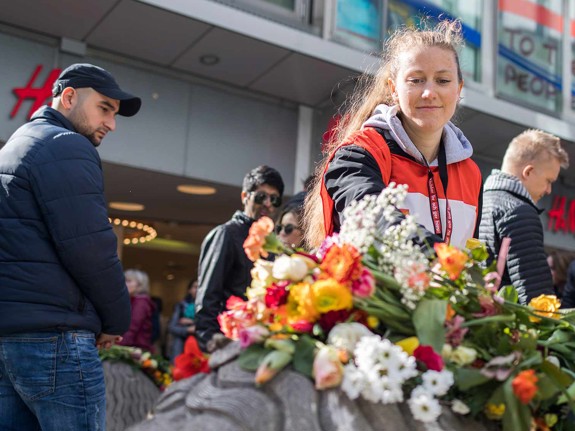 Flicka lägger blommor på Drottninggatan efter terrorattentatet