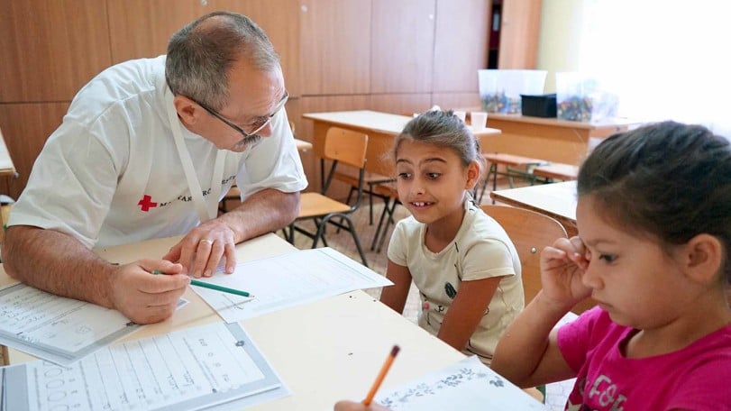 Vi hjälper ukrainska barn på flykt att förbereda sig för skolgång i Ungern. Här får Klaudia och Mirella öva på att skriva med stöd av vår volontär László Nagy.