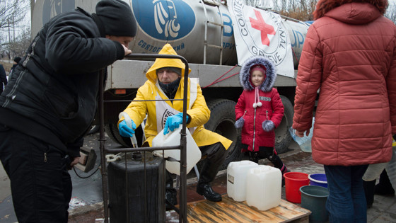 Liten flicka och vuxna med vattendunkar