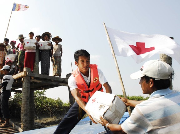 Röda Korset-volontär lastar av katastrofhjälp från båt.