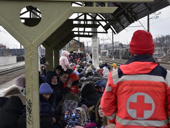 Röda Korset volontär och människor på flykt på en tågstation i Ukraina.