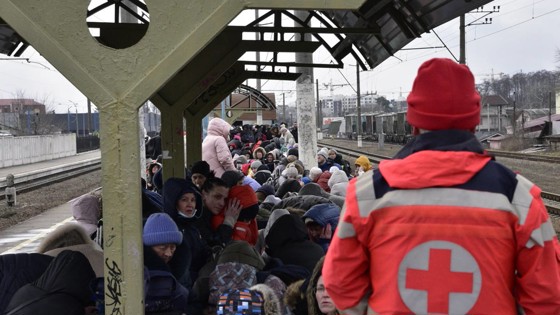 Röda korset volontär och flyktingar på en tågstation i Ukraina.