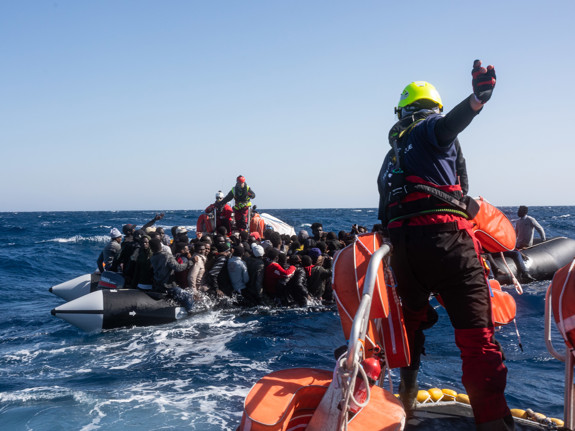 Röda Korset volontärer hjälper hjälper människor i gummiflottar.