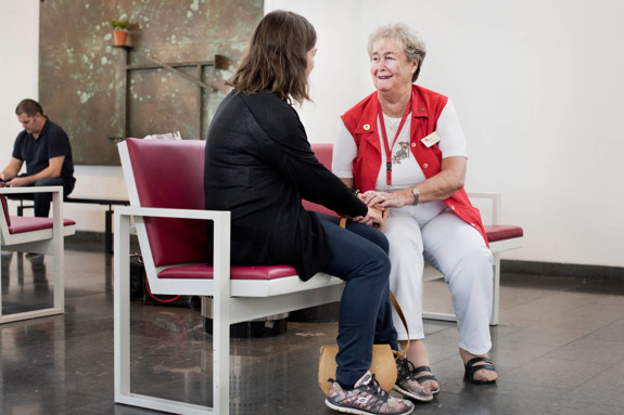 Syntolkning: En frivillig pratar med en besökare på sjukhuset.