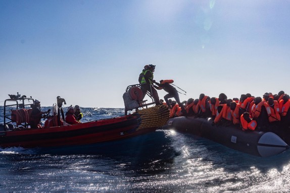 Volontärer hjälper flyktingar på gummiflotte.