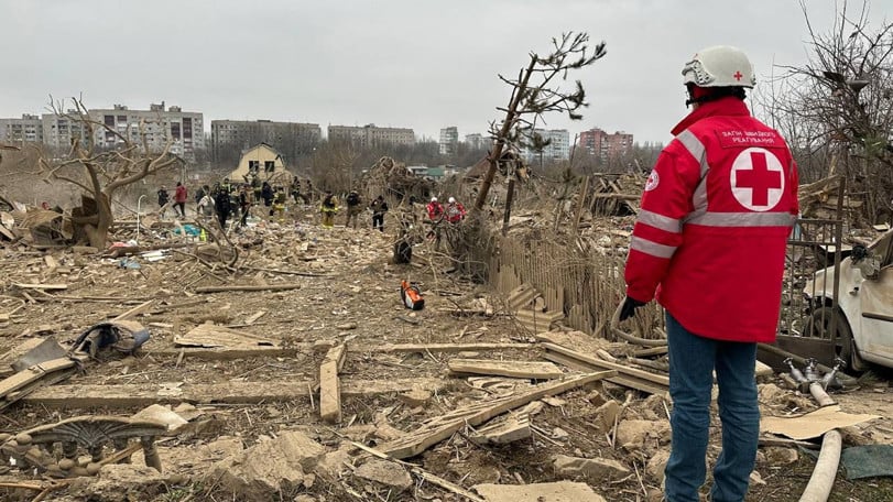 En volontär från Röda Korset står framför bråte vid en plats där räddningsarbete pågår.