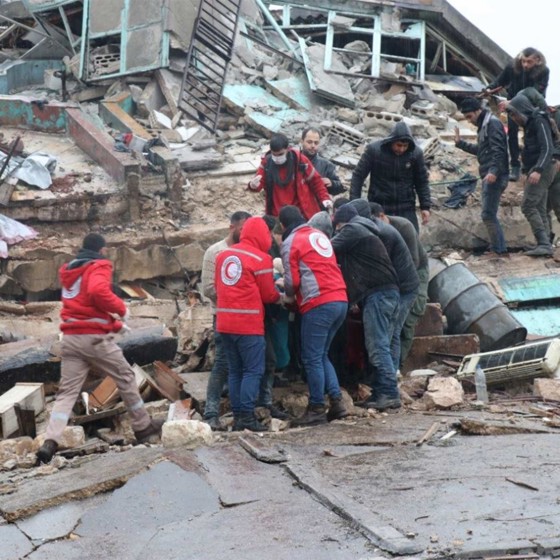 Röda korset volontärer tar ut människor ur raserat ut.