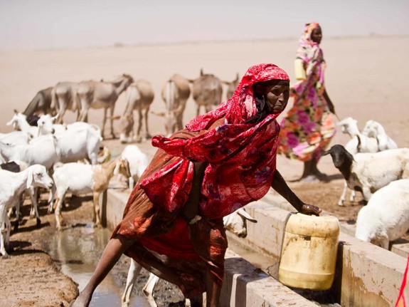 Rödklädd kvinna hämtar vatten vid torka i Kenya