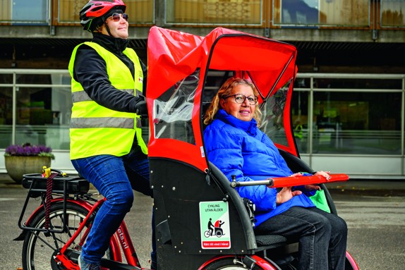 En volontär från Röda Korset kör en kvinna i en lådcykel.