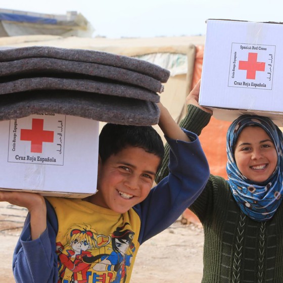 Pojke och flicka bär Röda Kors-paket